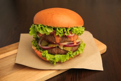 Photo of Board with tasty burger on wooden table, closeup