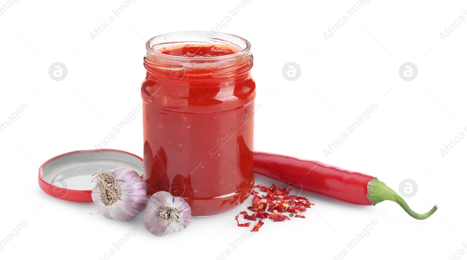 Photo of Spicy chili sauce in glass jar, garlic and pepper isolated on white