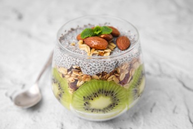 Photo of Delicious dessert with kiwi, chia seeds and almonds on light textured table, closeup