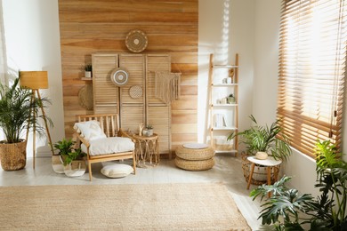 Stylish living room interior with comfortable wooden armchair and beautiful houseplants