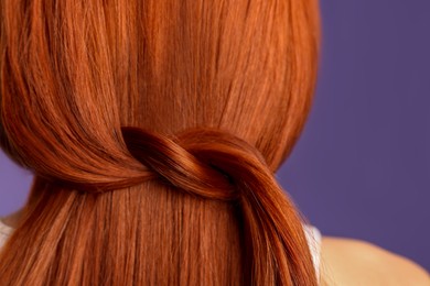 Woman with red dyed hair on purple background, back view