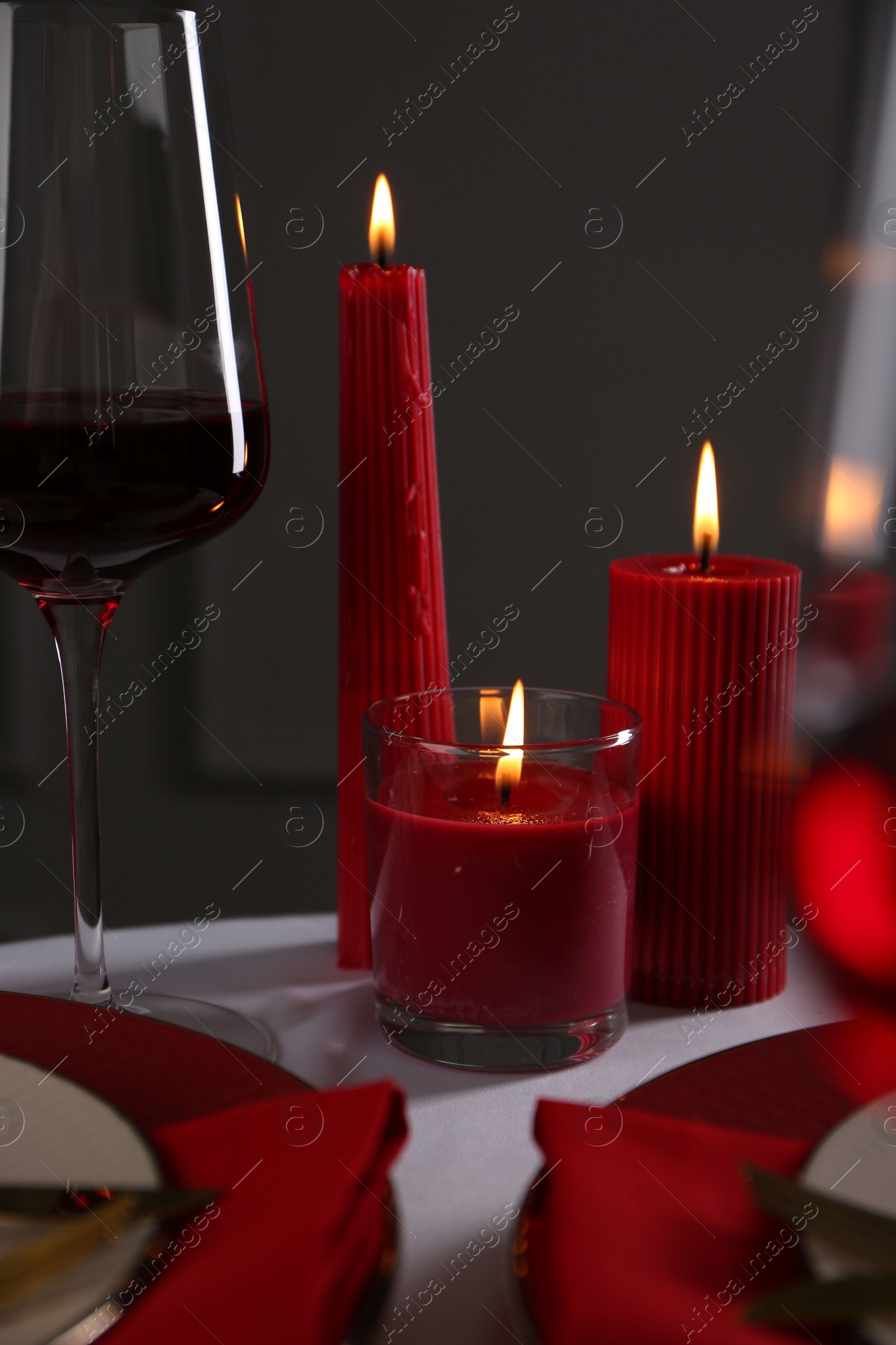 Photo of Place setting with red candles on white table. Romantic dinner