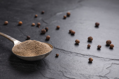 Photo of Ground black pepper and corns on black table, closeup