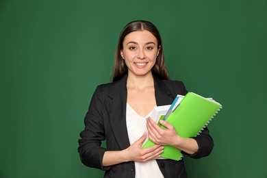 Photo of Portrait of young teacher with notebooks on green background