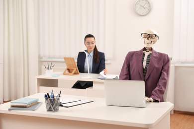 Photo of Young woman working with skeleton in office