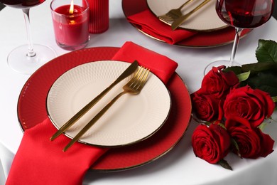 Photo of Place setting with roses and candle on white table. Romantic dinner