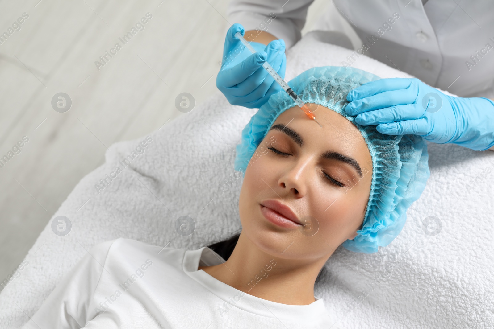 Photo of Doctor giving facial injection to young woman in clinic. Cosmetic surgery