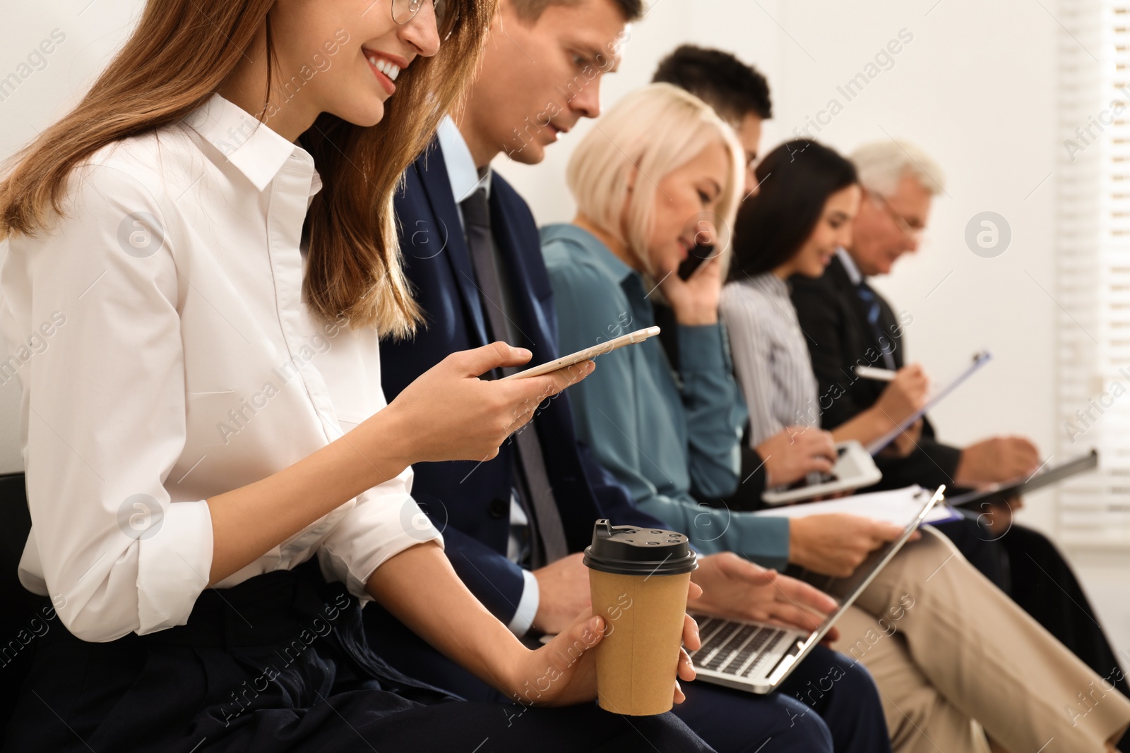 Photo of Woman with phone and cup of coffee waiting for interview in office, closeup