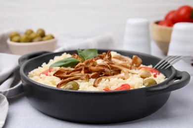 Tasty couscous with mushrooms, olives and tomatoes served on grey table, closeup