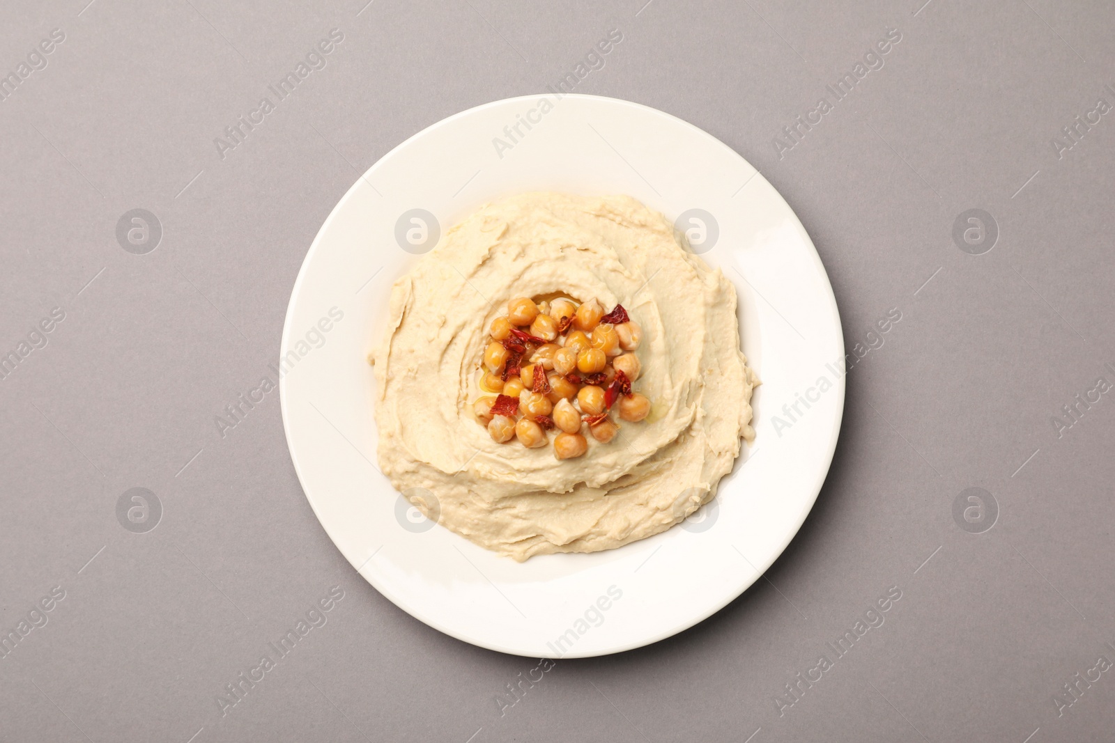 Plate of tasty hummus with chickpeas on grey background, top view Photo of Plate of tasty hummus with chickpeas on grey background, top view
