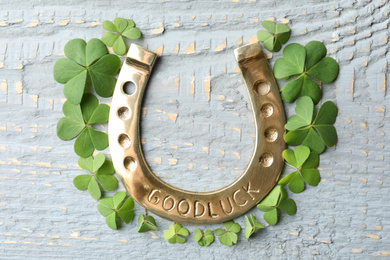 Photo of Clover leaves and horseshoe on wooden table, flat lay. St. Patrick's Day celebration