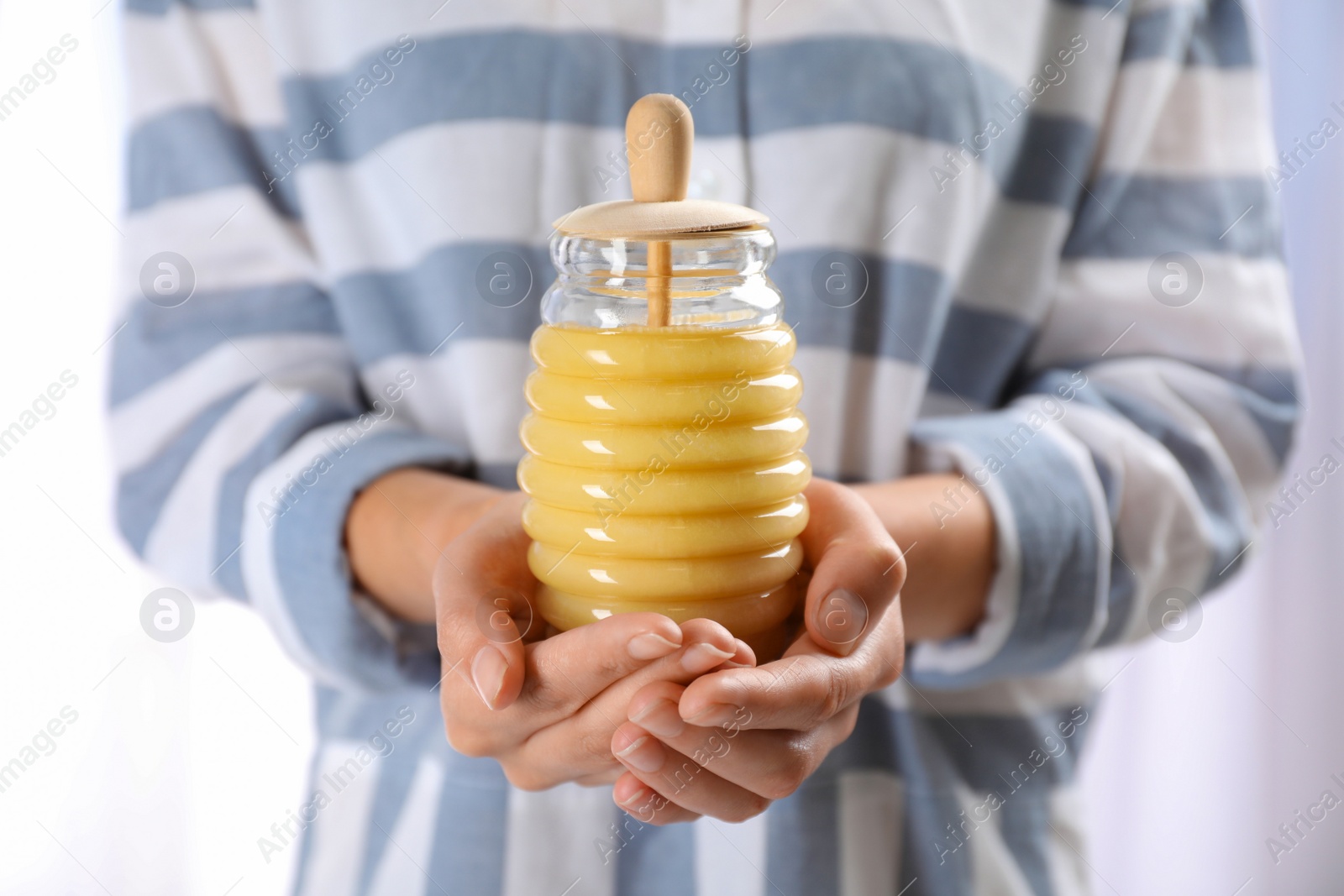 Photo of Woman holding glass jar with fresh sweet honey, closeup