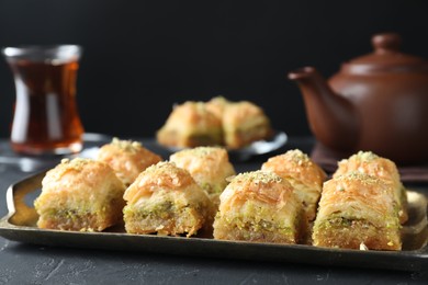 Photo of Delicious fresh baklava with chopped nuts on dark textured table, closeup. Eastern sweets