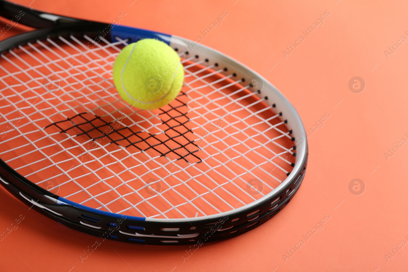Photo of Tennis racket and ball on orange background, closeup. Sports equipment