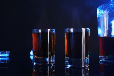 Photo of Alcohol drink in shot glasses and bottle on mirror surface