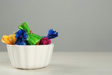 Photo of Candies in colorful wrappers on light table, space for text