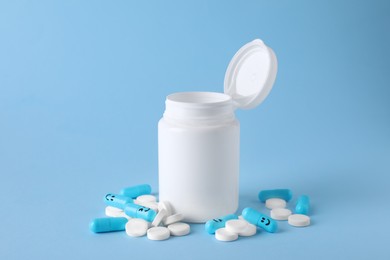 Photo of Antidepressants with happy emoticons and medical jar on light blue background