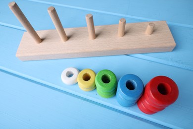 Photo of Stacking and counting game pieces on light blue wooden table, closeup. Motor skills development