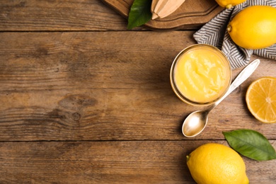 Delicious lemon curd and fresh fruits on wooden table, flat lay. Space for text