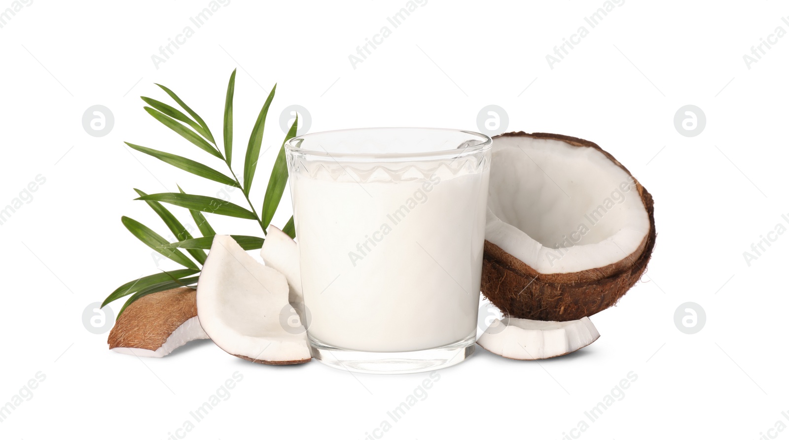 Photo of Glass of delicious vegan milk, coconut pieces and green leaves on white background