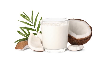 Glass of delicious vegan milk, coconut pieces and green leaves on white background