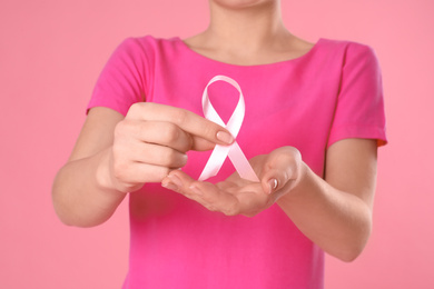 Woman holding pink ribbon on color background, closeup. Breast cancer awareness