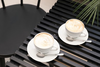 Ceramic cups of aromatic coffee with foam on wooden table in cafe