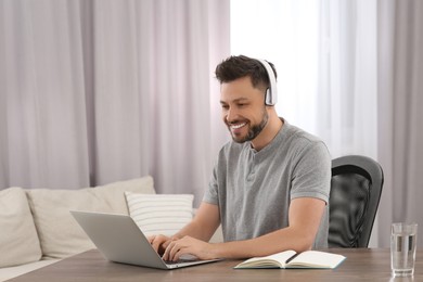 Photo of Online translation course. Man in headphones typing on laptop at home