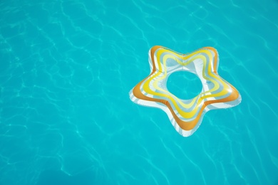 Photo of Star shaped inflatable ring floating in swimming pool on sunny day, above view. Space for text