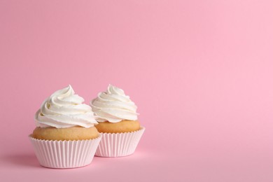 Delicious cupcakes with white cream on pink background. Space for text