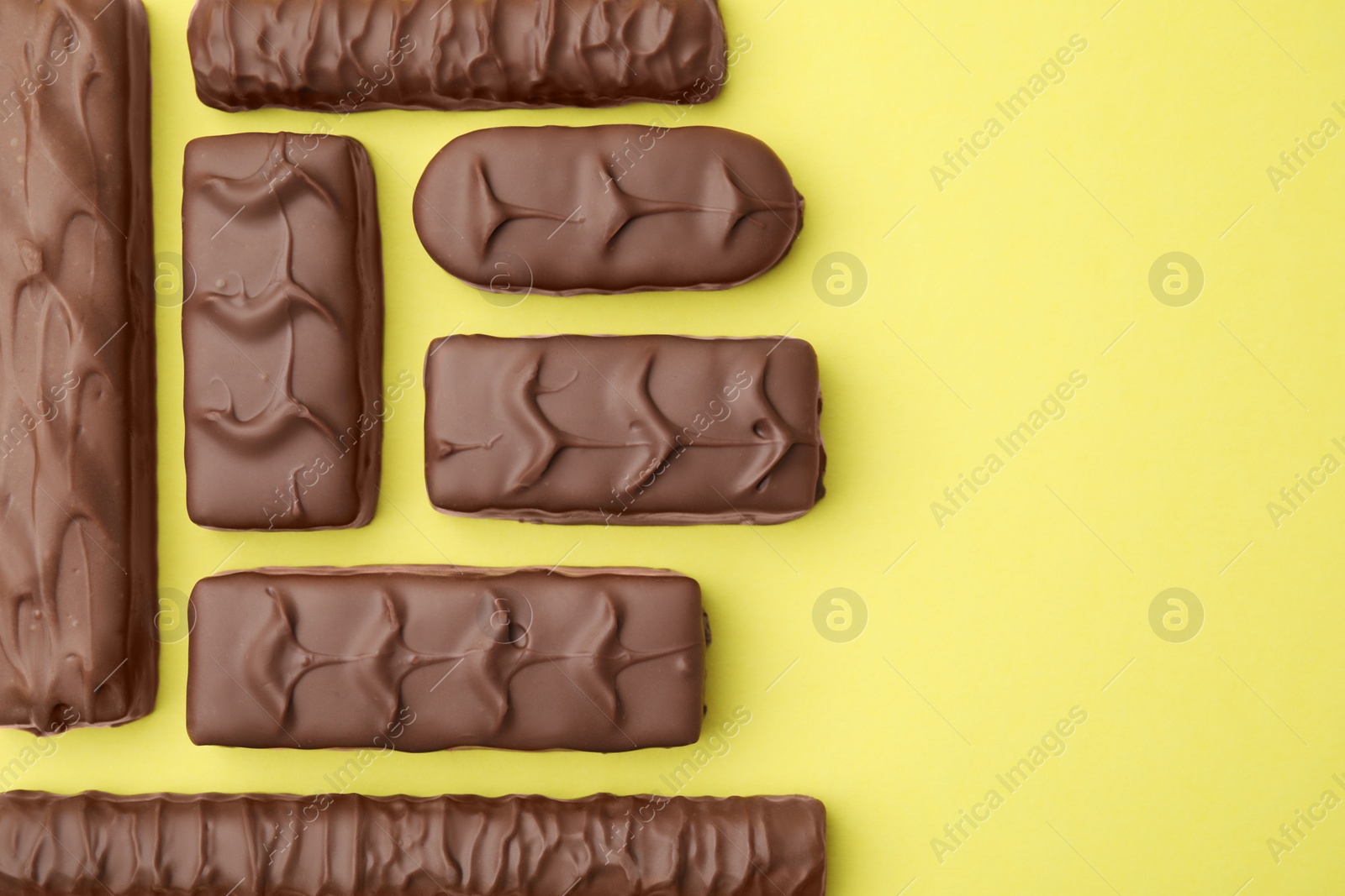 Photo of Different tasty chocolate bars on yellow background, flat lay. Space for text
