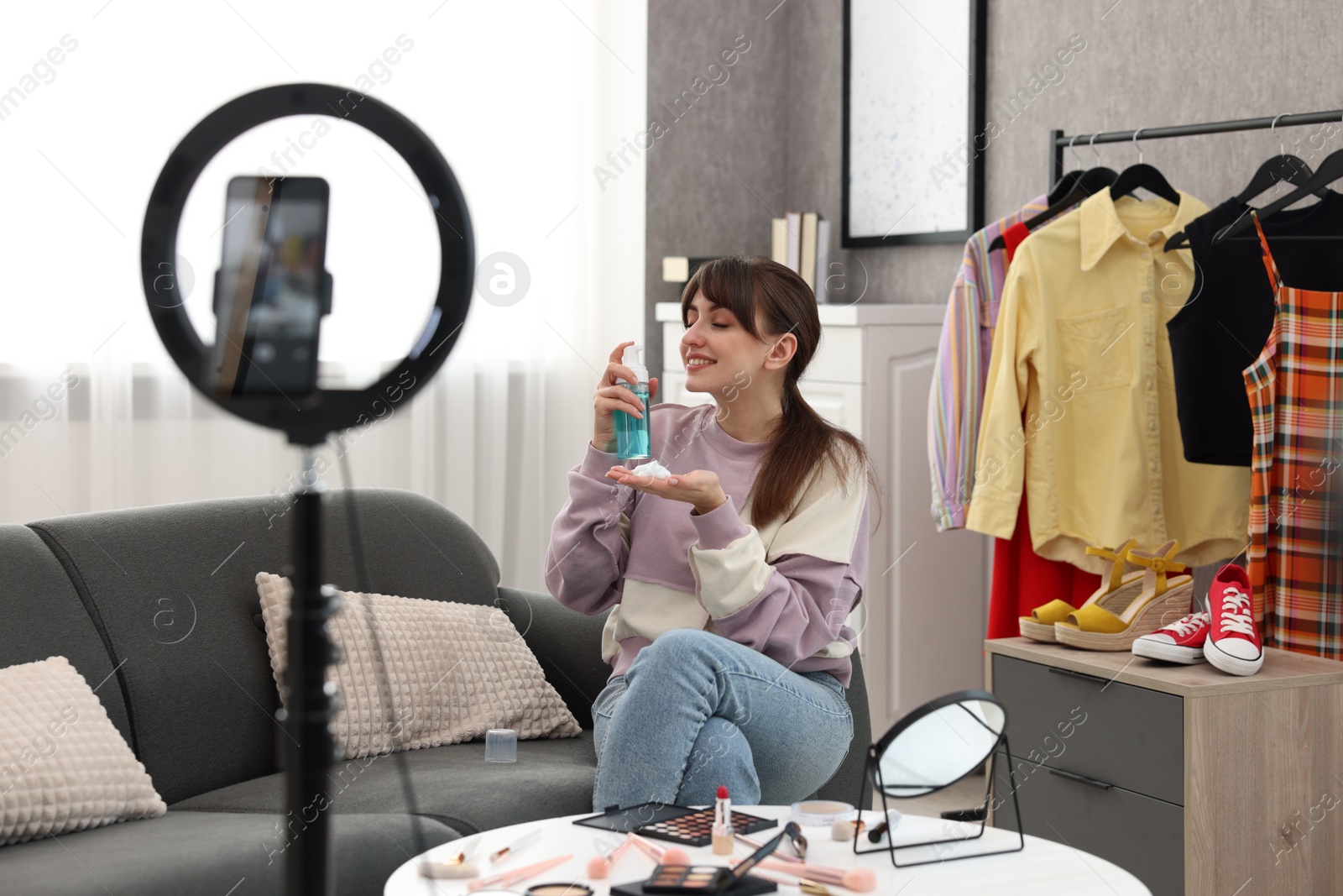 Photo of Smiling beauty blogger recording video while testing cosmetic products at home