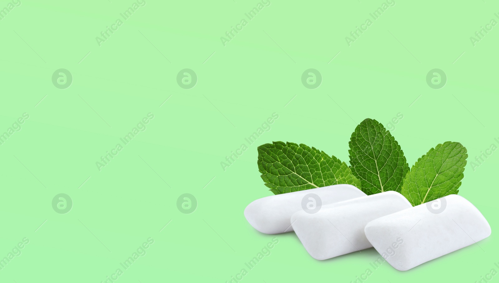 Image of Menthol chewing gum pillows and mint leaves on pale light green background, space for text