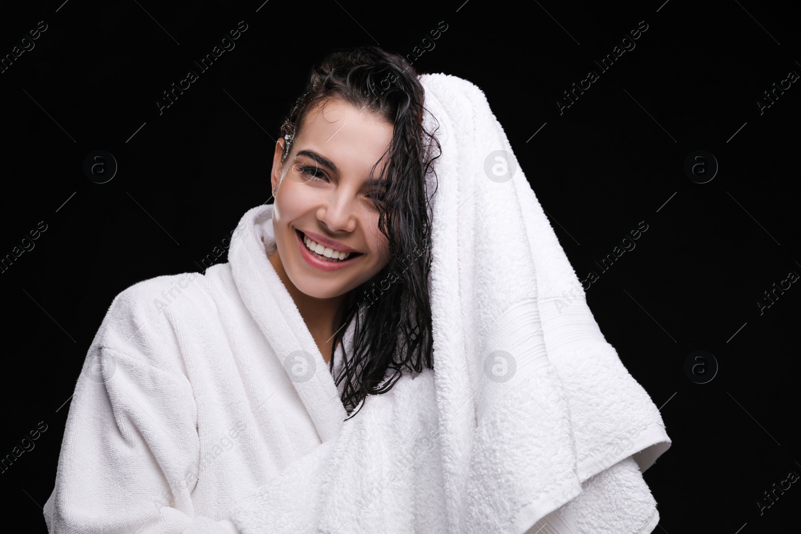 Photo of Pretty woman drying hair with towel after washing on black background