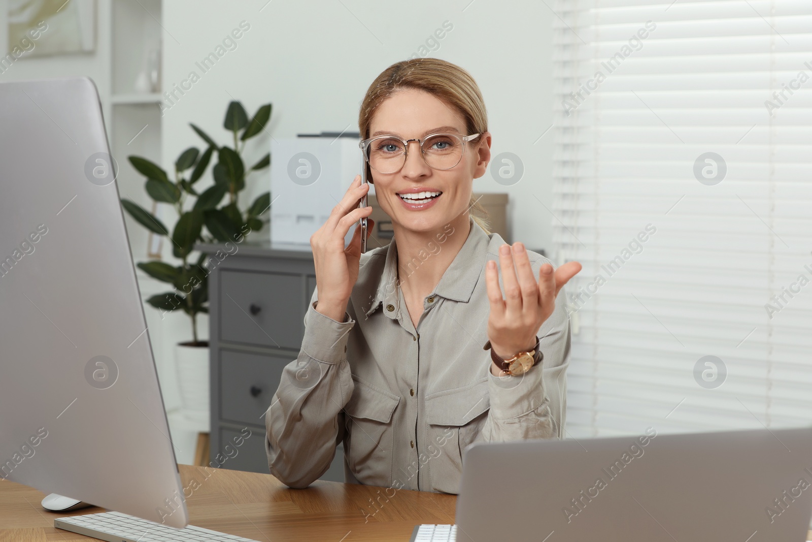 Photo of Professional accountant talking on phone while working at wooden desk in office