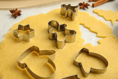 Photo of Dough and cookie cutters on light table, closeup. Christmas biscuits