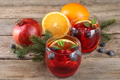 Aromatic Christmas Sangria drink in glasses, fir branches and ingredients on wooden table