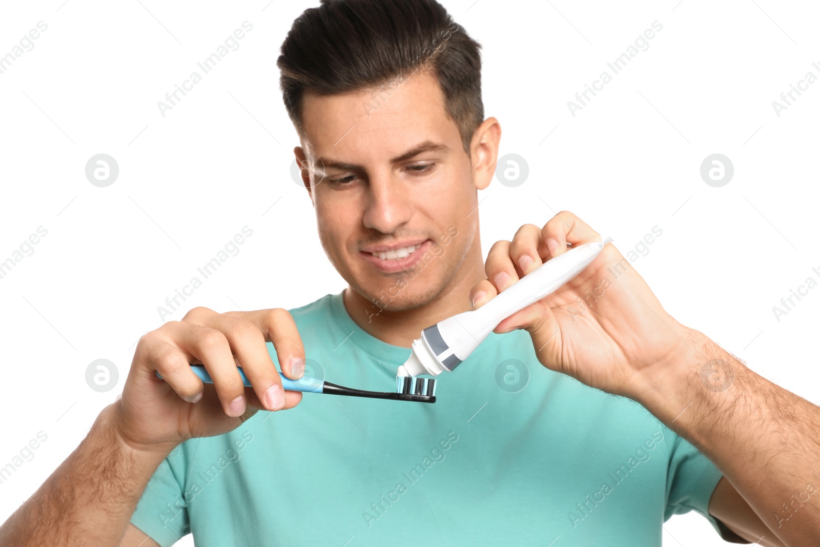 Photo of Man applying toothpaste on brush against white background