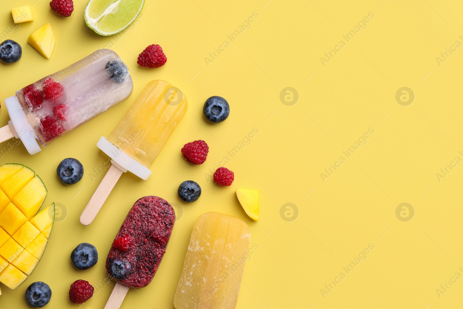 Photo of Different fruit ice pops on light yellow background, flat lay. Space for text