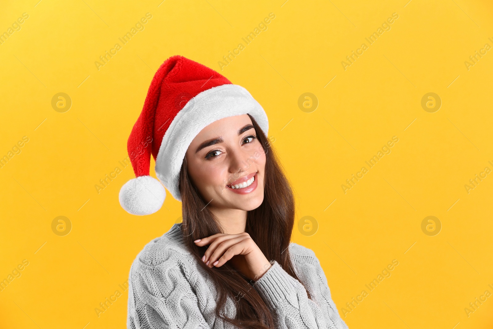 Photo of Beautiful woman wearing Santa Claus hat on yellow background