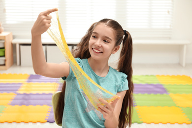 Preteen girl playing with slime in room