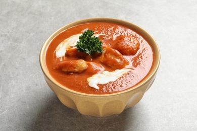 Photo of Bowl of delicious butter chicken on grey table. Traditional indian Murgh Makhani