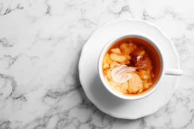 Photo of Cup with black tea and milk on marble table, top view