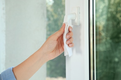 Photo of Woman using tissue paper to open window indoors, closeup