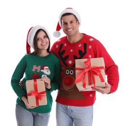 Beautiful happy couple in Santa hats and sweaters holding Christmas gifts on white background