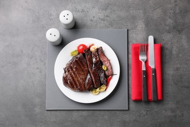 Photo of Delicious grilled beef meat served on grey table, flat lay