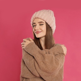 Photo of Beautiful young woman in hat and sweater on pink background. Winter season