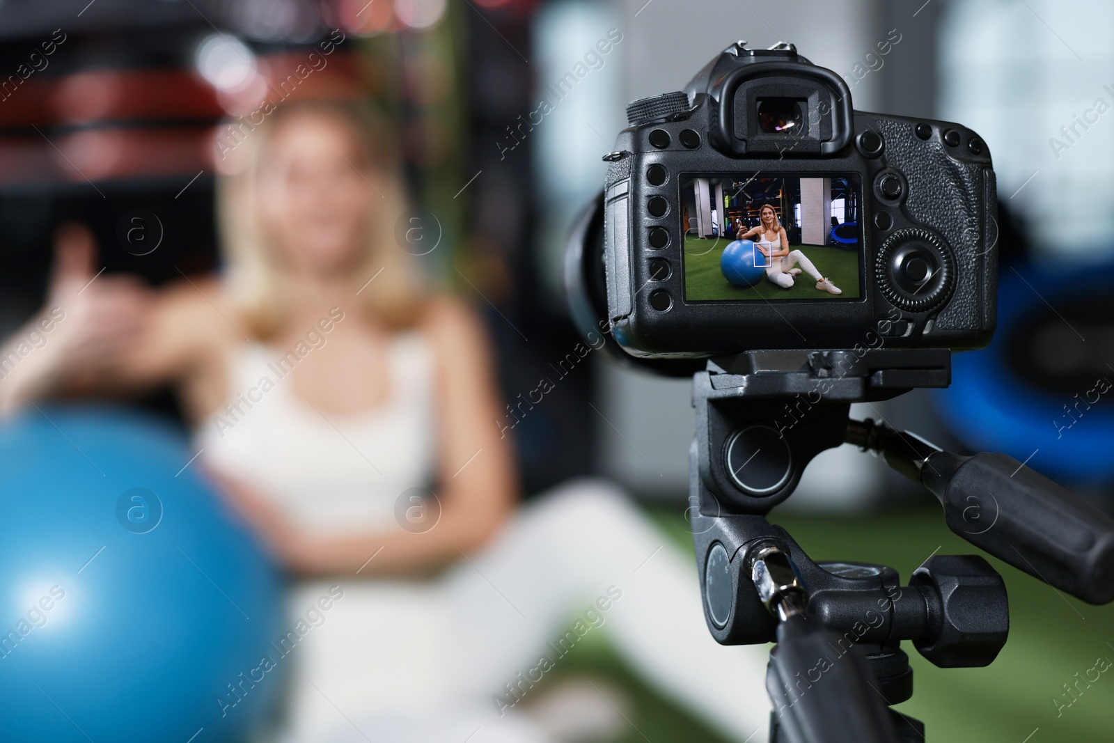 Photo of Fitness trainer recording online classes in gym, focus on camera. Space for text