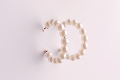 Elegant earrings with pearls on white background