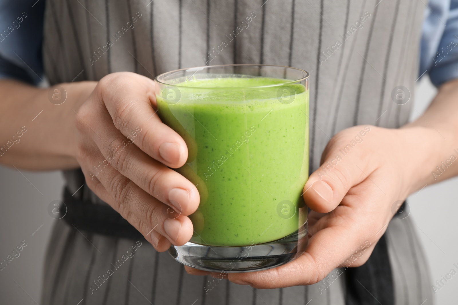 Photo of Woman holding tasty fresh kale smoothie, closeup